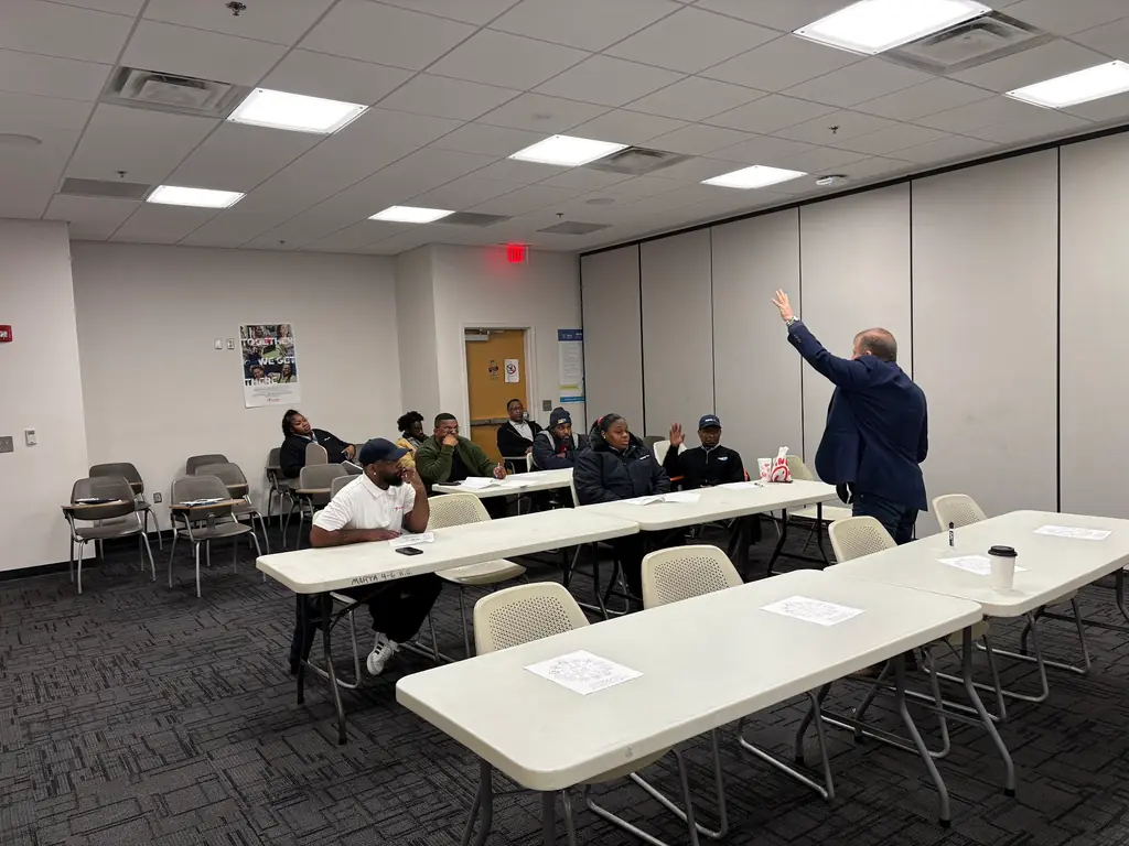 Bill Parsons mid gesture teaching a room of transit staff, MARTA marked table in the foreground